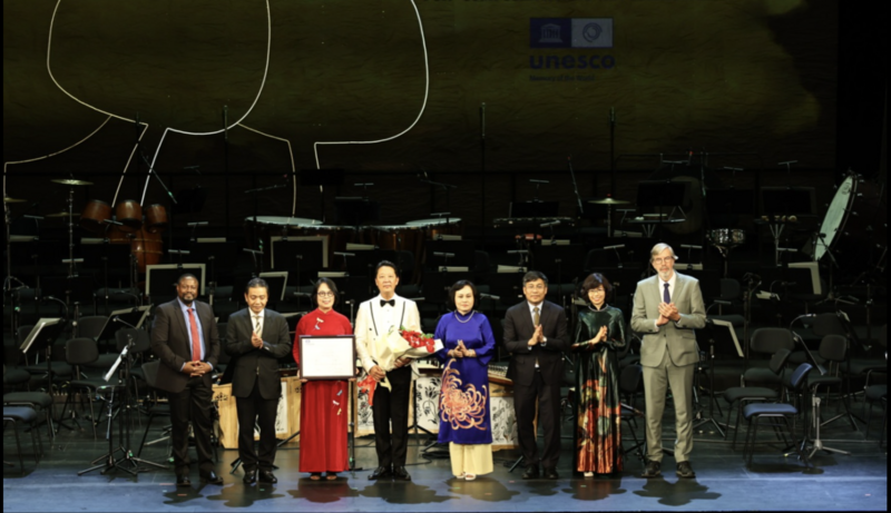 Thứ trưởng Bộ VHTTDL Hoàng Đạo Cương, Tiến sĩ Fackson Banda, Trưởng Bộ phận Di sản Tư liệu, Chương trình Ký ức Thế giới của UNESCO, Thứ trưởng Thường trực Bộ Ngoại giao Nguyễn Minh Vũ, Chủ tịch Hội đồng Tư vấn quốc tế Chương trình Ký ức Thế giới Johannes Joseph Maria Bos trao Bằng Di sản Tư liệu Thế giới của UNESCO cho gia đình cố nhạc sĩ Hoàng Vân.