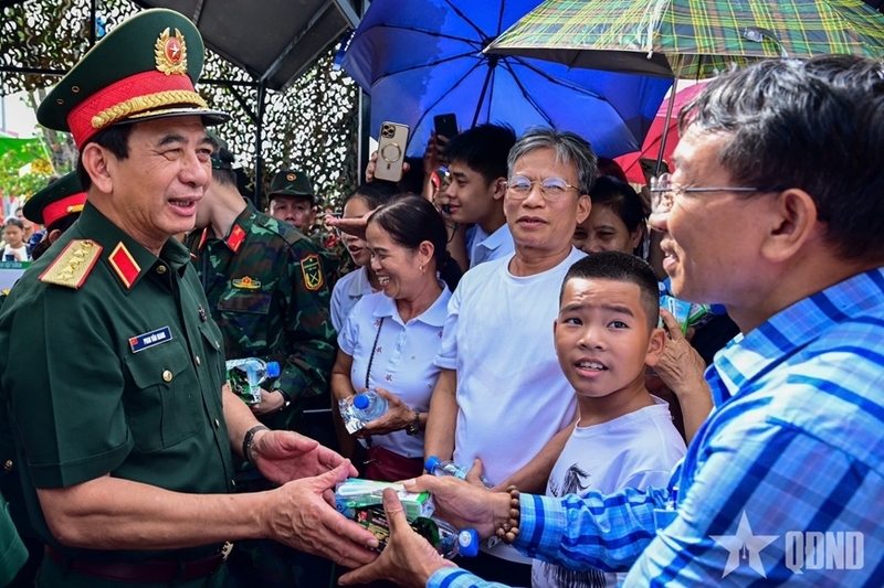 Đại tướng Phan Văn Giang, Uỷ viên Bộ Chính trị, Phó Bí thư Quân uỷ Trung ương, Bộ trưởng Bộ Quốc phòng tặng nước, sữa, lương khô cho người dân tại triển lãm. Ảnh: QĐND