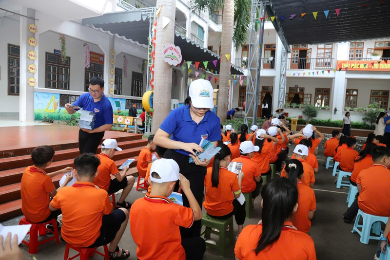 Tuyên truyền viên phát tờ rơi cho các em học sinh